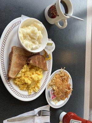 Grits,scrambled eggs with cheese,wheat toast & hash browns and a cup of coffee.