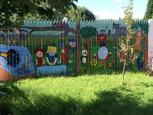 Children painted this whimsical fence mixing Alice in Wonderland with Animal from the Muppets.