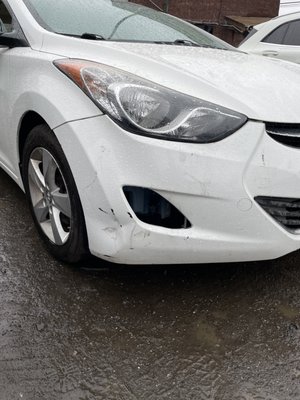 A car with a dent on the bumper and under front headlight