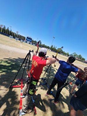 Two vision-impaired archers using tactile adaptive equipment to shoot archery. Distance is 30 meters (33 yards).