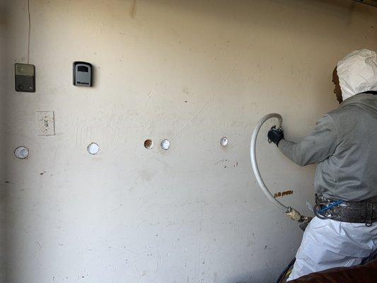 Team Leader Kareem filling in holes in the garage.