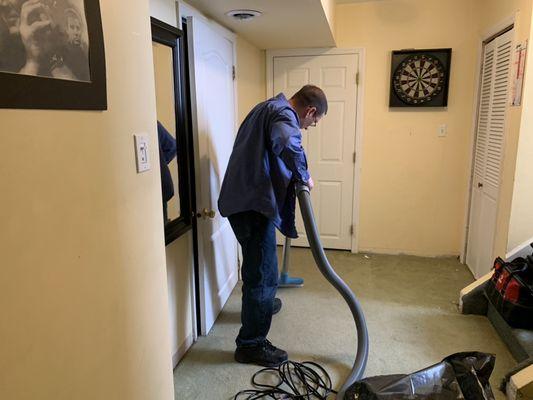 Joe Kielbasa using the flood pumper HVE 3000 extraction tool to remove water from wet carpet & padding in basement after a pipe break