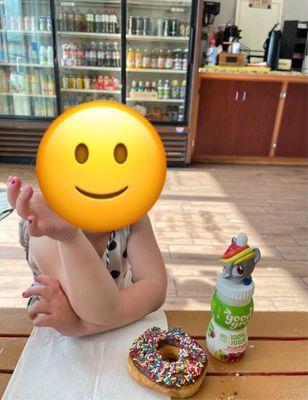 Granddaughter enjoying a chocolate glazed sprinkle donut and a drink