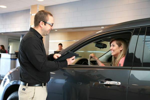 Service Advisor Kris Alderman greets a customer in the drive