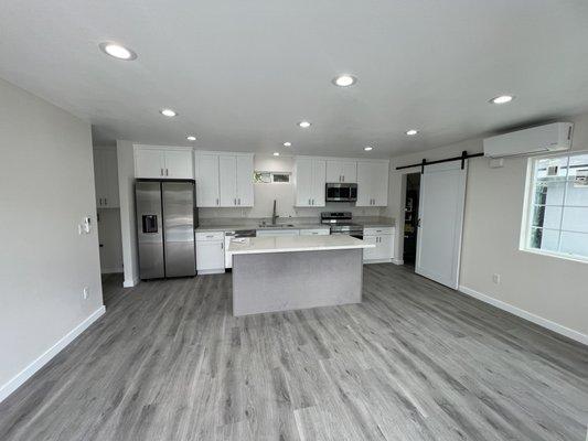 Completed living room with kitchen appliances and split system hvac.