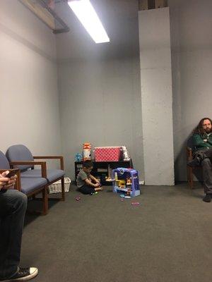 Spacious waiting area with toys for kids and siblings waiting for family in class.