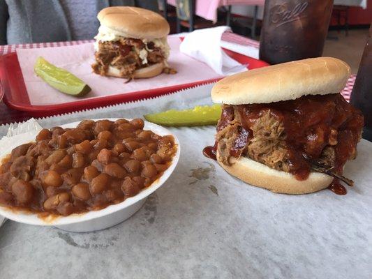 Pulled pork sandwich, one is "topped" (with coleslaw), baked beans, and a pickle. Sweet tea in a mason jar seals the deal. Delicious!