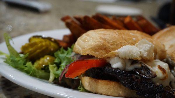 Savory prime rib sandwich with shaved prime rib, peppers, onions and crispy sweet potatoes fries.