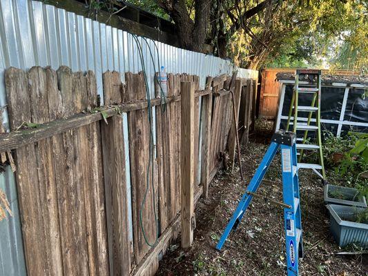 Prior to tear down of an old fence after completing a metal fence just behind it