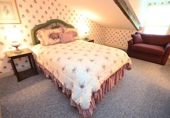 The Parsley Room is a carpeted room with original exposed ceiling beams, a queen bed, and a bathroom with a shower.