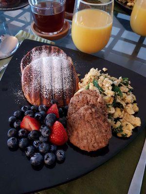 Brioche French toast served with spinach, scrambled eggs, turkey sausage and with fresh blueberries and strawberries.