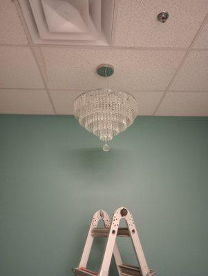 Removed a standard light fixture and installed a chandelier along with removing stained tiles