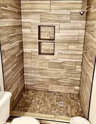 Custom shower with wood plank tile and two shampoo niches.