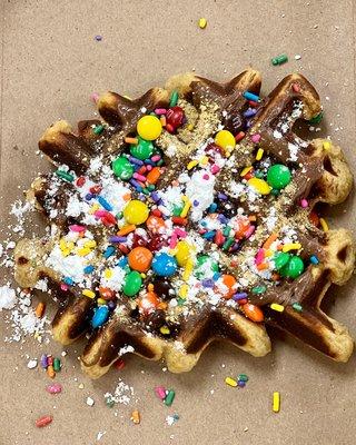 The Leo Special. Chocolate chip protein waffle with fingertips, m&m's, Nutella and powdered sugar toppings.