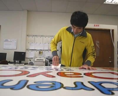 Owner, Linh Tran creating and finishing a sign.