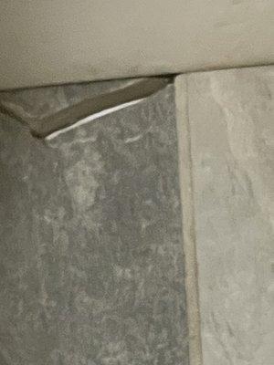 Cracked tiles in bathroom around commode.