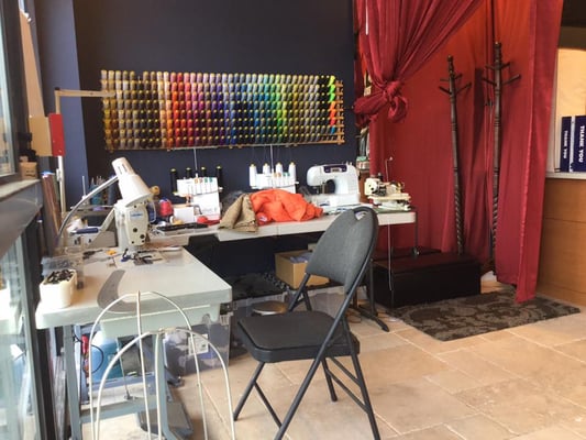 tailoring desk at the front of the shop with the changing room beside it.