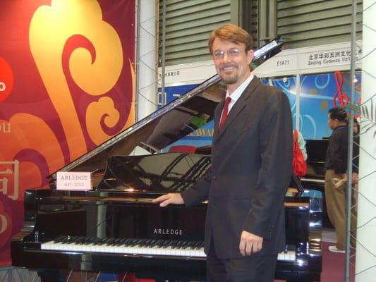 I stand in front of the Arledge 232 Grand piano / original design and build being exhibited at the Messa Frankfort music fair Shanghai 2008