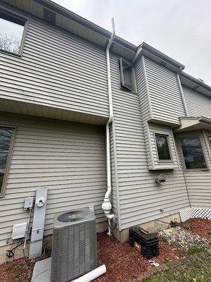 Exterior radon system with white PVC pipe.