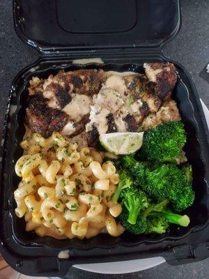 Jerk chicken served over brown rice with 2 sides