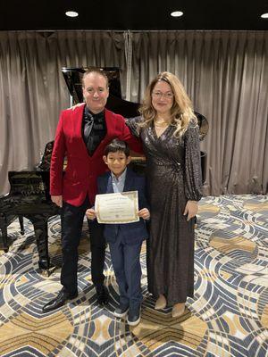 Receiving his latest certificate at his piano performance.