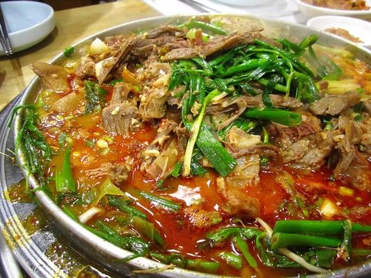 Close up of goat stew with enoki mushrooms and water parsley