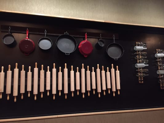 Unique decor on the wall with rolling pins, skillets and bottles.