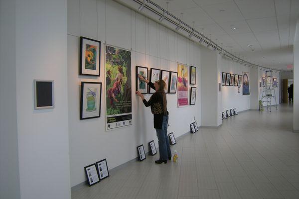 Cheryl Chappell installing a traveling exhibit for the Syracuse Poster Project at Upstate Cancer Center, February, 2017.