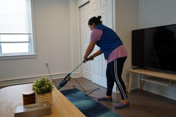 cleaning lady is vacuuming the carpet