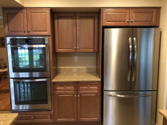 Fabuwood Hallmark Pecan Cabinets, Dupont Toasted Almond Quarts Counters, Standard Satin Nickel Knobs and Vinyl Tile Floor.