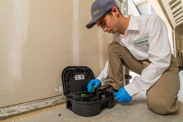 Green Pest Management technician re-filling a rodent bait station.