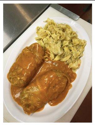 Cabbage rolls with a side of cabbage and noodles.