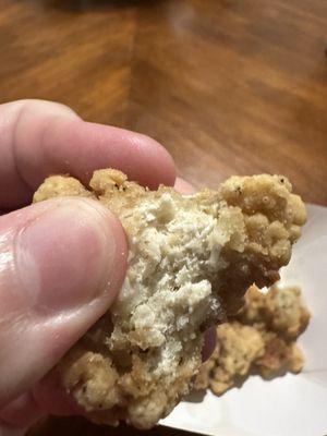 Photo of a piece of bitten popcorn chicken.