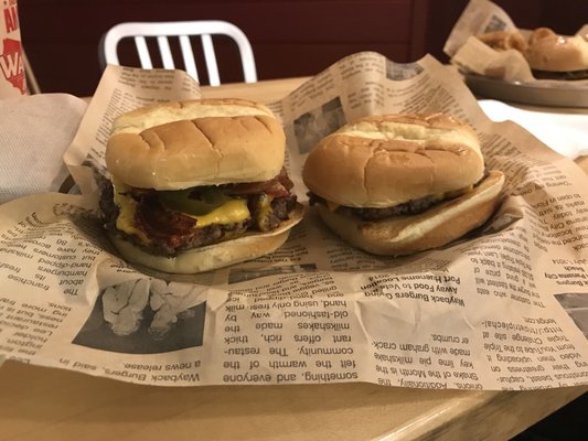 Double cheese burger with bacon, jalapeños, onions, and mustard. Single cheeseburger with ketchup and mustard on right.