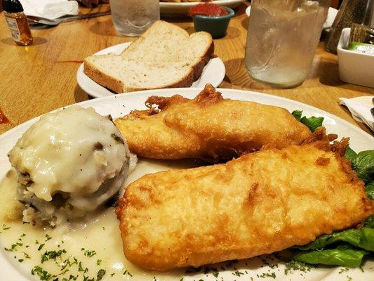 Fish dinner with mashed potatoes and chicken gravy.  Fresh bread.