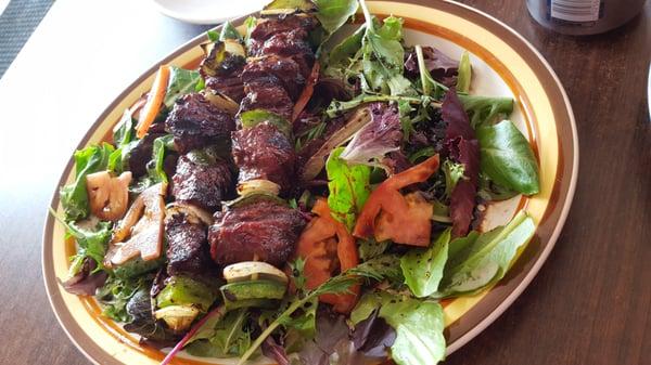 Beef kabobs over salad