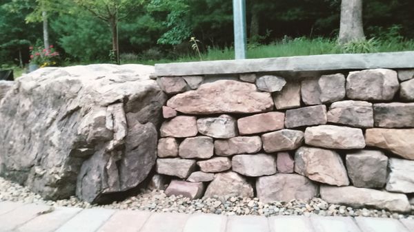 Drystack retaining wall with mortared capstone and boulder end.