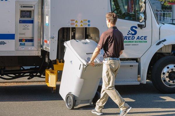 96 gallon container being wheeled to shredding truck. We shred it right there at your location.