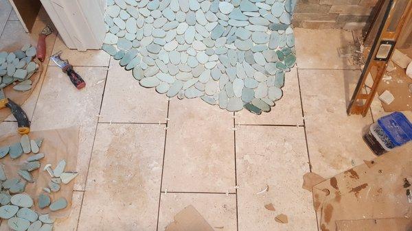 The blue stones are cascading out of the shower area onto the main floor.