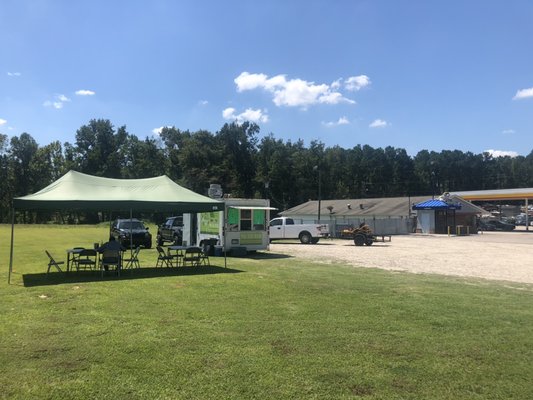 Taco truck at the gas station and tables set up to enjoy the environment.