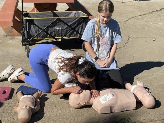 Two girls learning CPR to become a babysitter.