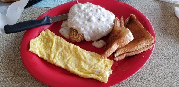 Country fried steak with gravy,  scrambled eggs,  and toast.