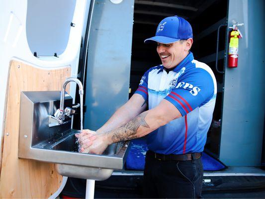 Express Plumbing technician washing his hands using his hand washing station.