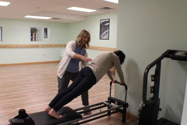 Working with a client on the pilates reformer for core strengthening.