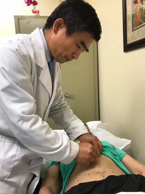 Dr. Lu is treating the patient with acupuncture.