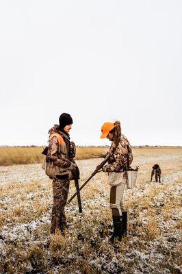 Two hunters review their shotguns while hunting pheasants with his Wirehaired Pointing Griffon in Gallatin County, Montana.