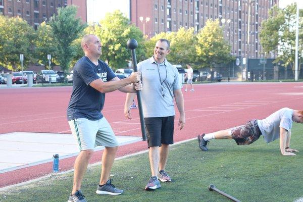 Coach Aaron works with a fitness bootcamp attendee on strength and form at an event in the Boston area...