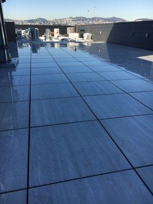 2x2 Porcelain Pavers Installed On Top Of Adjustable Pedestals. Pedestals Sit Atop Waterproof Membrane on Roof.