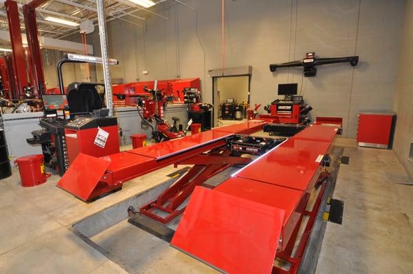 Alignment scissors rack with console, tire changer, balancer, and brake lathe.