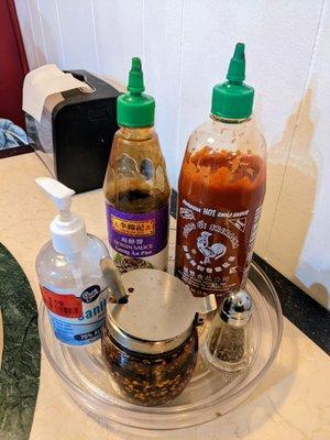 Table condiments include hoisin sauce, Sriracha, and red chili oil.